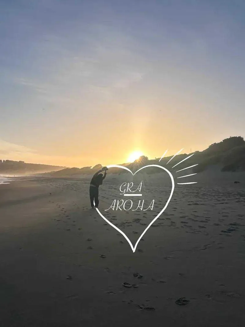 A heart drawn in the sand, lettered Grá Aroha